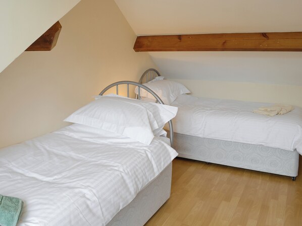 Twee enkele bedden in een kamer met houten balken en een schuine kap.