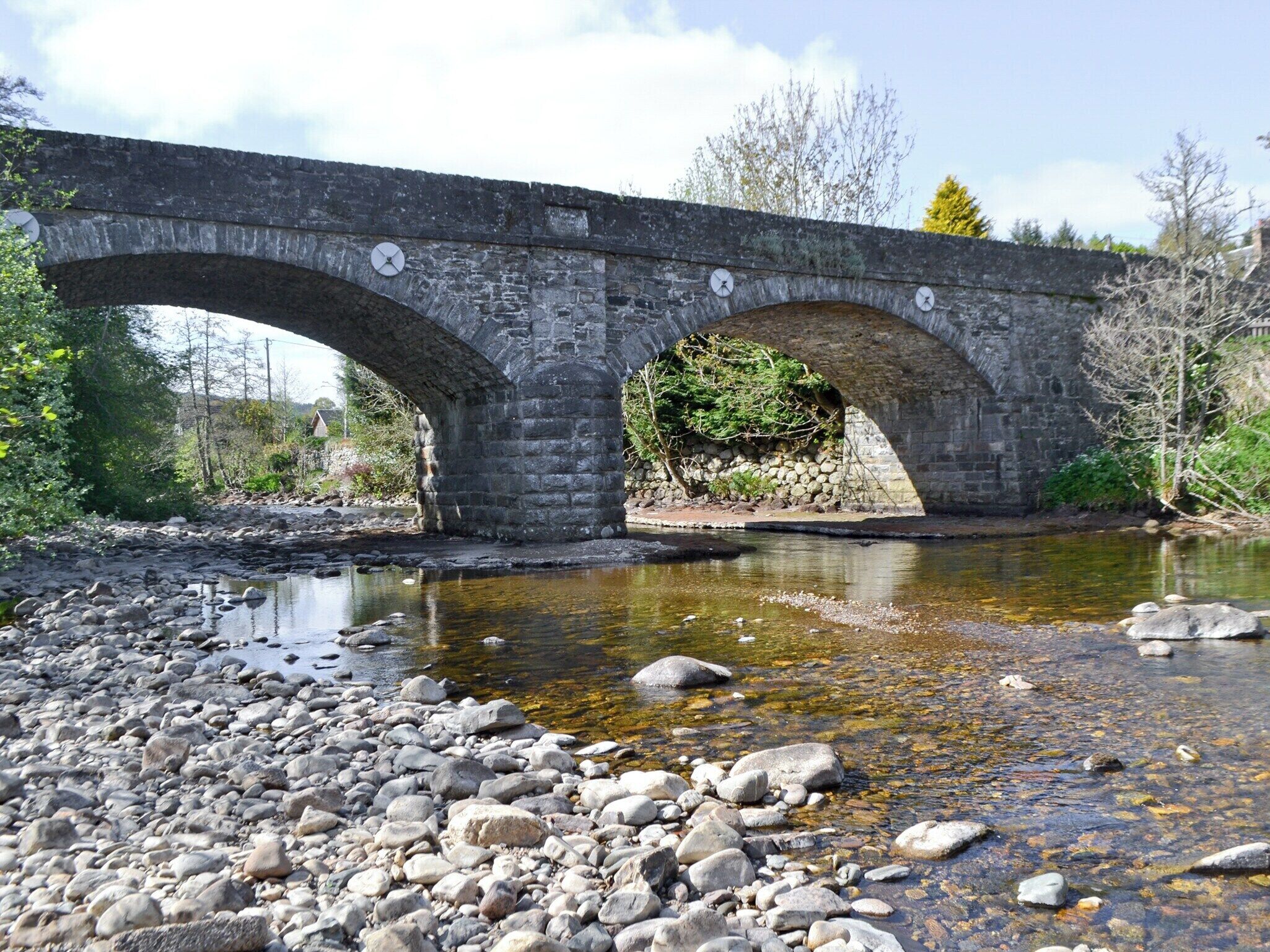 A stone bridge over a river with a rocky riverbank.