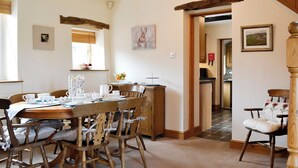 A dining area with a wooden table and chairs, a chandelier, and a view of the kitchen through an open doorway. - Lakes, mountains or beaches - how about the best of all three. (Bigrigg, near Egremont)