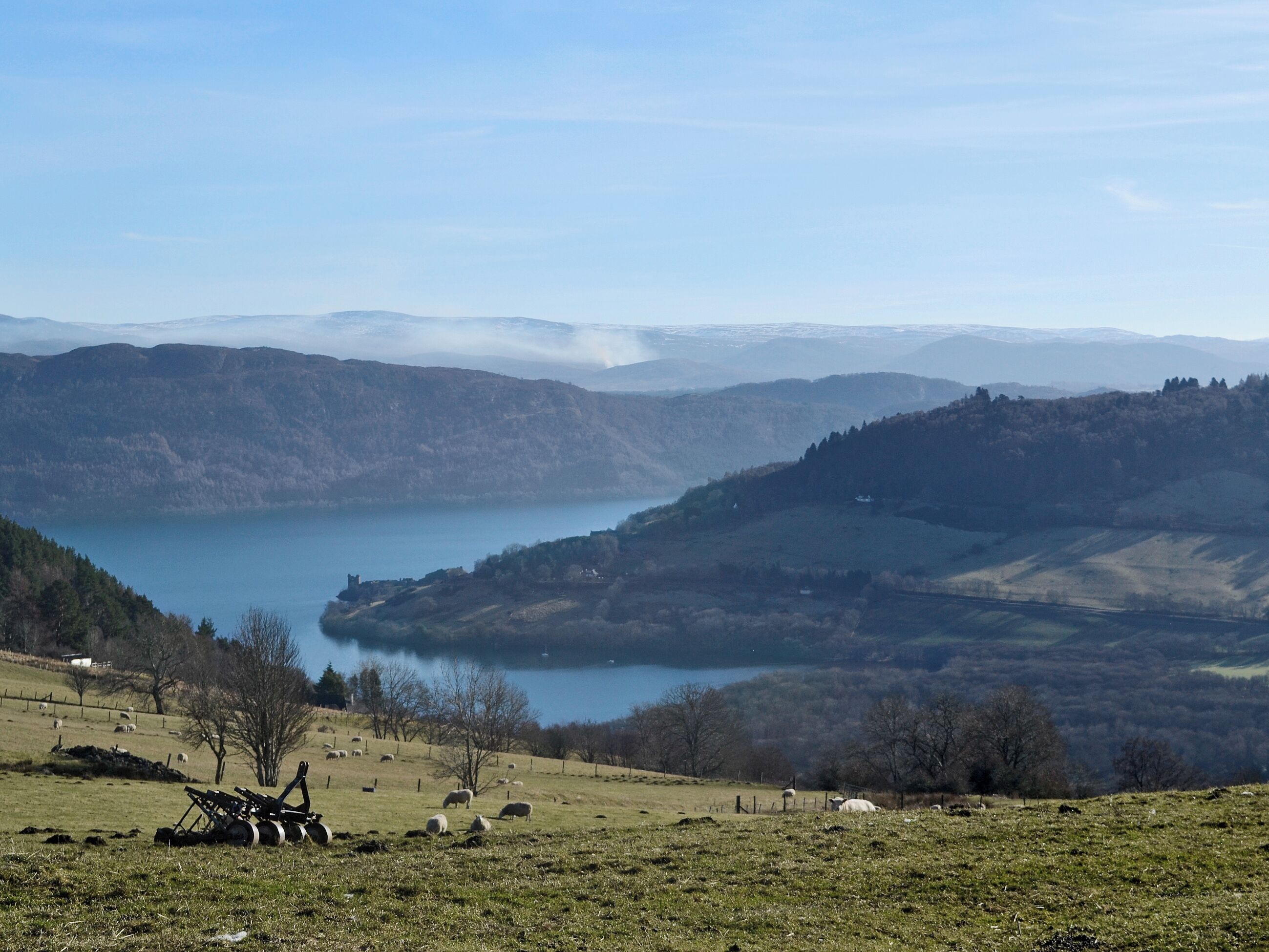 Vista panorámica de un valle con un lago, rodeado de colinas y vegetación escasa.