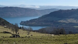A panoramic view of a valley with a lake, surrounded by hills and sparse vegetation.