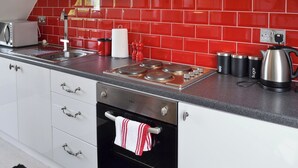 Una cocina moderna con salpicadero de baldosas rojas, electrodomésticos de acero inoxidable y un hervidor.