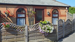 Une maison en briques avec un toit en tuiles, une porte en bois et des jardinières remplies de fleurs.