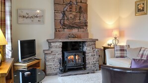 A cozy living room with a stone fireplace, a television, and a comfortable couch. - 2 bedroom accommodation in Bigrigg, near Egremont (Bigrigg, near Egremont)