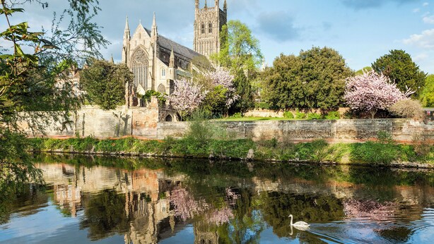 A historic church with Gothic architecture, a calm river reflecting its structure, and blooming cherry trees. - 0 bedroom accommodation in Upper Welland, Malvern (Upper Welland, Malvern)