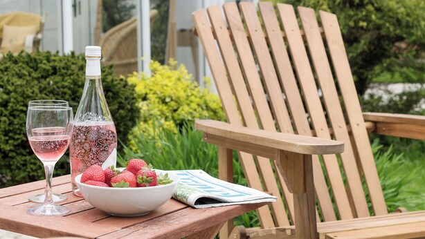 A wooden chair, a table with a bowl of strawberries, two wine glasses, and a bottle of wine. - 3 bedroom accommodation in Denford, near Thrapston (Denford, near Thrapston)