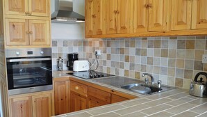 Una cocina con armarios de madera, horno doble, cafetera, tostadora y hervidor.