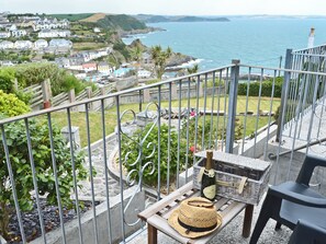 A balcony with a wicker basket, a bottle, and a straw hat.
