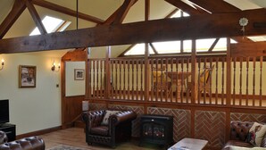 Un salón acogedor con chimenea, sofás de cuero y estructura de techo de madera.