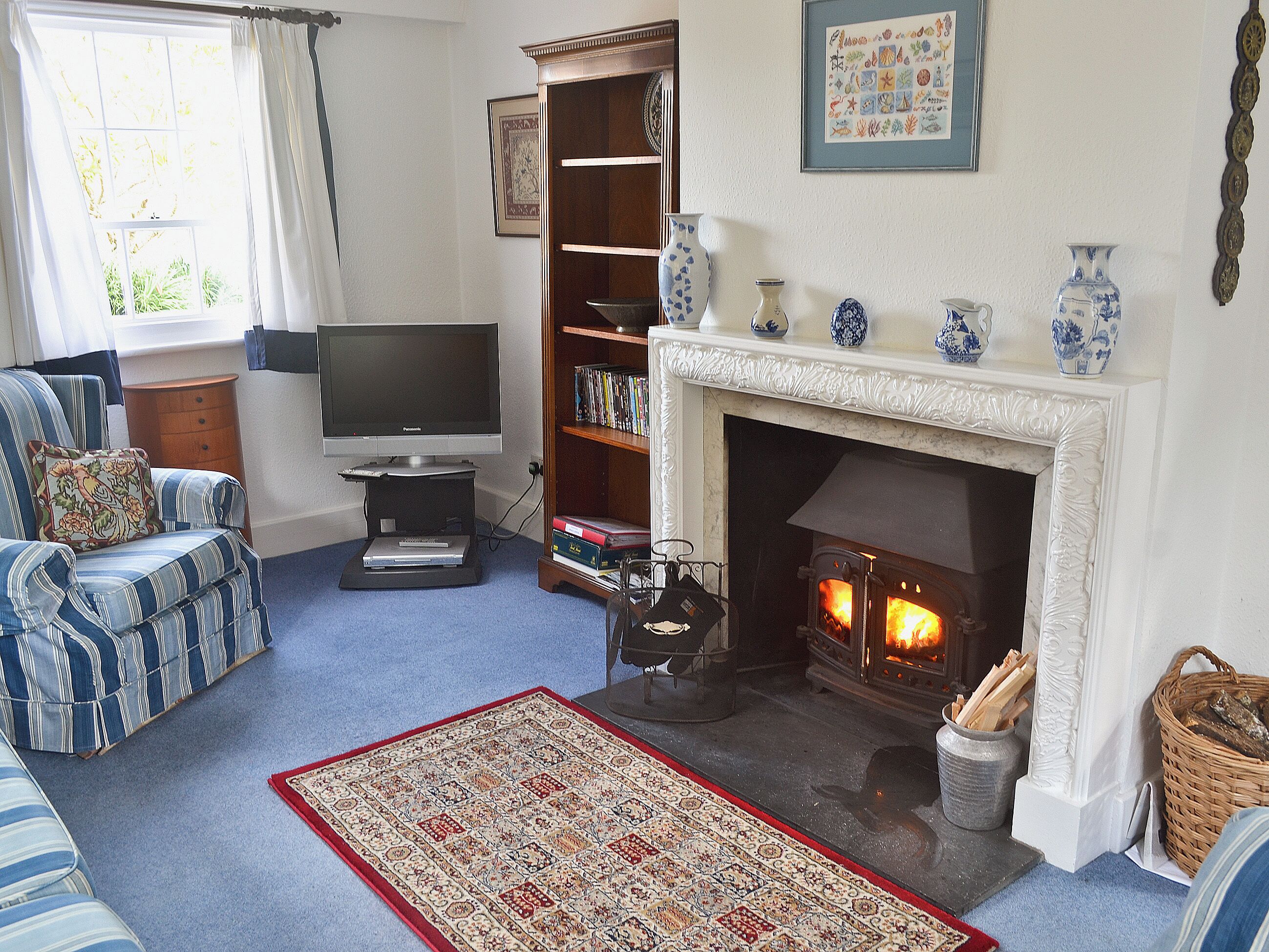 A living room with a fireplace, a television, a bookshelf, and a patterned rug.