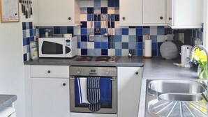 A kitchen with white cabinets, a microwave, a stove, and a sink.
