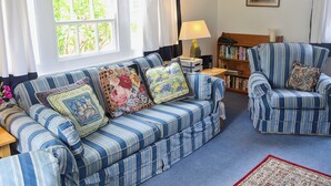 A living room with a striped sofa, armchair, and a bookshelf.