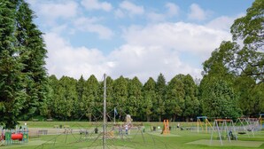 Un parc équipé d’aires de jeux, d’une structure d’escalade et d’une zone herbeuse.
