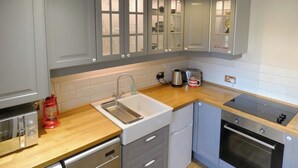 Une cuisine de taille réduite avec des meubles gris, un évier, une cuisinière et un lave-vaisselle.