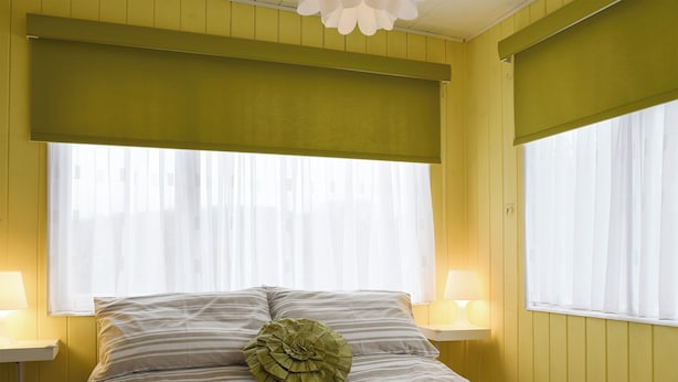 Un lit avec une literie à rayures, un coussin décoratif vert et une pile de serviettes.