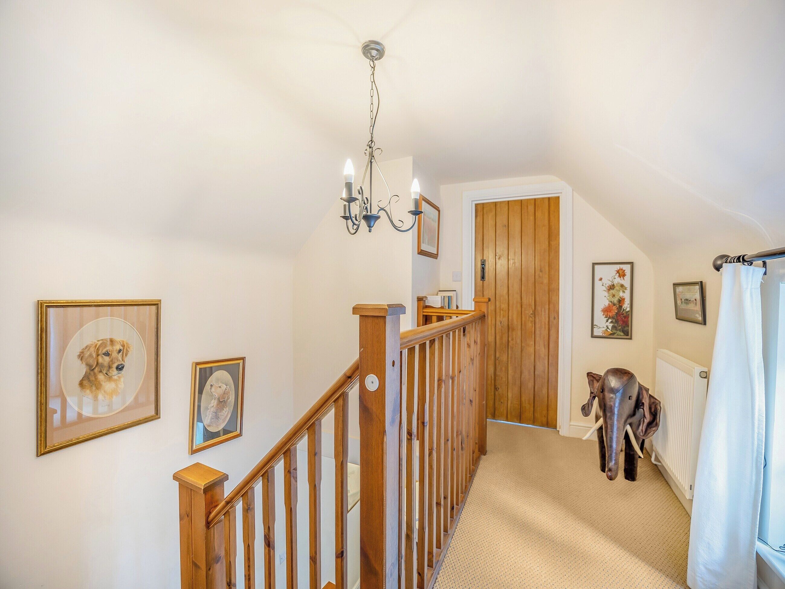 A staircase with wooden railings leading to a door, a chandelier, and framed pictures on the walls.
