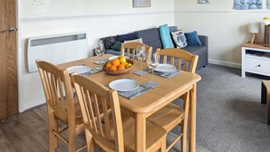 A wooden dining table set with plates, glasses, and a bowl of fruit. - 1 bedroom accommodation in Happisburgh (Happisburgh)