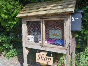 A wooden shop structure with a sign reading "Shop" and a directional sign pointing right. - 3 bedroom accommodation in Woodacott, near Holsworthy (Woodacott, near Holsworthy)