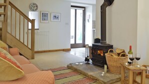 Ein gemütliches Wohnzimmer mit Kamin, Treppe und Blick ins Freie.