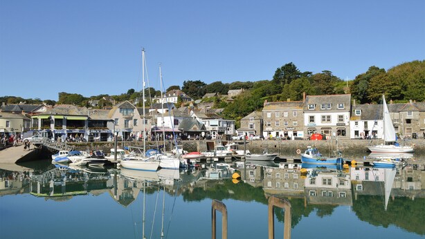A harbor with boats docked, a café, and buildings with shops.