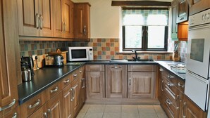 Una cocina con armarios de madera, microondas, pileta y ventana.