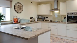 Een moderne keuken met een centraal eiland, roestvrijstalen apparatuur en lichtkleurige keukenkastjes.