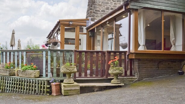 A stone building with a wooden balcony and large windows.