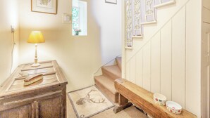 A staircase with white railings and a wooden bench. There are framed pictures on the walls and a lamp on a wooden table. - 1 bedroom accommodation in Lyth, near Wick (Lyth, near Wick)