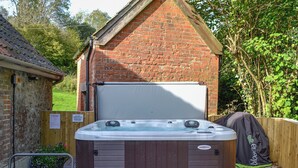 Un jacuzzi en un patio trasero con una casa de ladrillo al fondo.