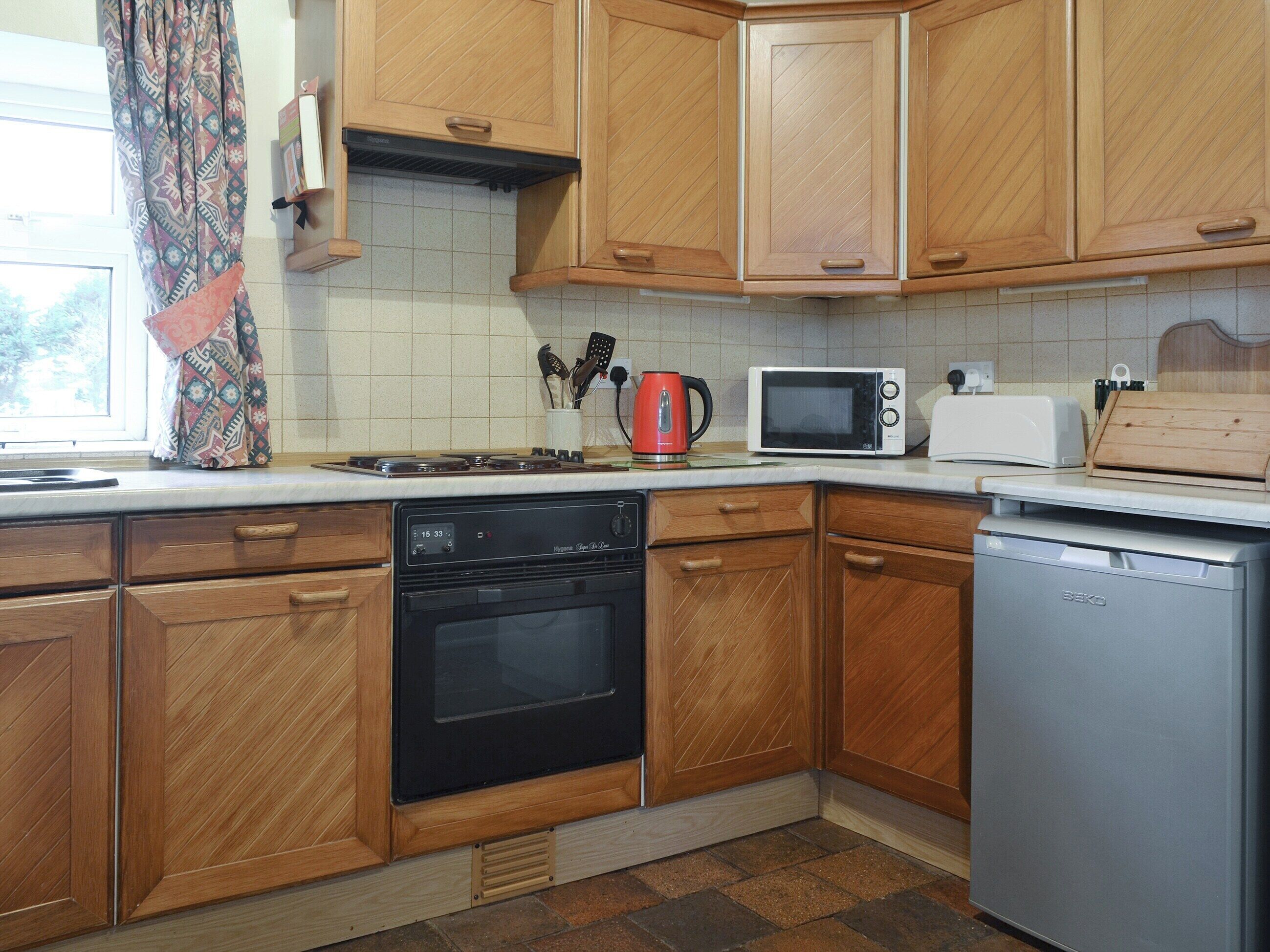 A kitchen with wooden cabinets, a microwave, a toaster, and a dishwasher.