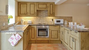A kitchen with wooden cabinets, a built-in oven, a microwave, and a sink.