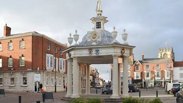 A historic pavilion with a dome and columns, surrounded by brick buildings and a church in the background.