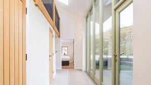 A hallway with a bed, a wooden door, and a glass door leading outside. - 5 bedroom accommodation in Llangoedmor, near Cardigan (Llangoedmor, near Cardigan)