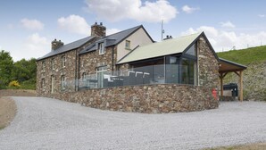 A stone building with a large glass window, a metal roof, and a gravel driveway. - 5 bedroom accommodation in Llangoedmor, near Cardigan (Llangoedmor, near Cardigan)