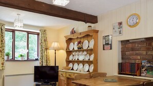 A cozy room with a wooden dining table, chairs, a television, and a bookshelf filled with books and decorative items. - 2 bedroom accommodation in Burscough, near Southport (Burscough, near Southport)
