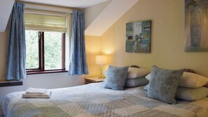A bedroom with a large bed, a window with curtains, a nightstand with a lamp, and a painting on the wall. - 2 bedroom accommodation in Burscough, near Southport (Burscough, near Southport)