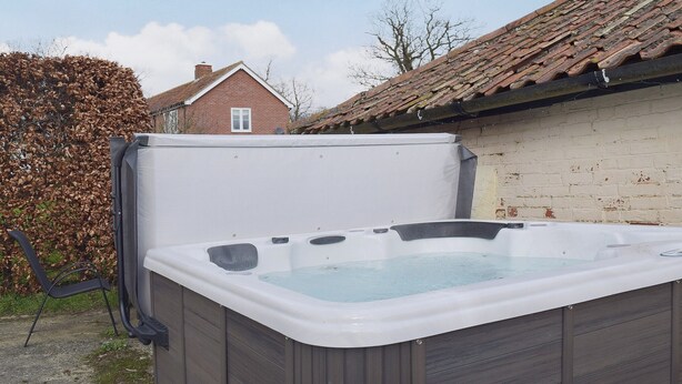 A hot tub in an outdoor setting with a brick house in the background. - 2 bedroom accommodation in Debenham, near Framlingham (Debenham, near Framlingham)