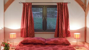 A bedroom with a bed, two bedside lamps, a window with curtains, and a vase with flowers on the nightstand. - 3 bedroom accommodation in Ninfield, near Battle (Ninfield, near Battle)