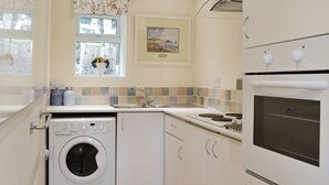 A compact kitchen with a washing machine, a sink, and an oven. - 1 bedroom accommodation in Gunville, near Newport (Gunville, near Newport)