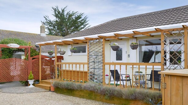 A house with a covered porch, outdoor seating, and a gravel driveway. - 1 bedroom accommodation in Gunville, near Newport (Gunville, near Newport)