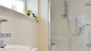 A bathroom with a white sink, toilet, and glass-enclosed shower. - 1 bedroom accommodation in Gunville, near Newport (Gunville, near Newport)