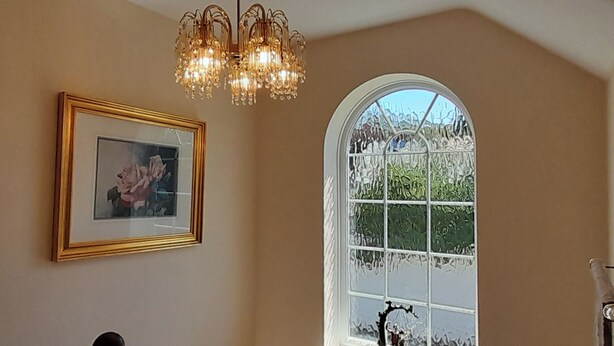 Eine Treppe mit einem Chandelier, einem gerahmten Bild und einem Fenster mit Blick auf Bäume.