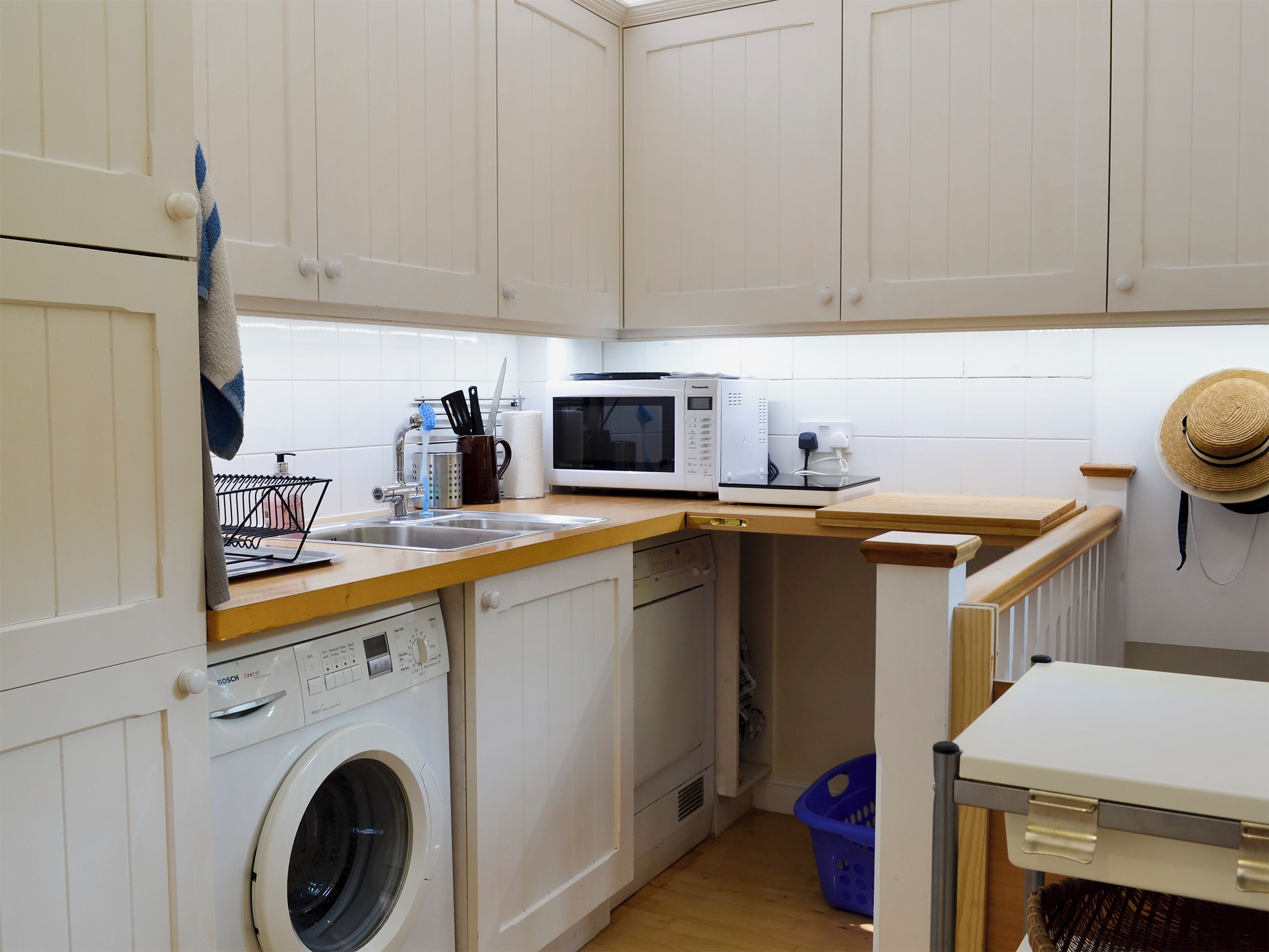 Une cuisine compacte équipée d’un lave-linge, d’un four à micro-ondes et d’un évier.