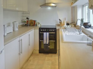 A compact kitchen with a built-in oven, a sink, and a window.