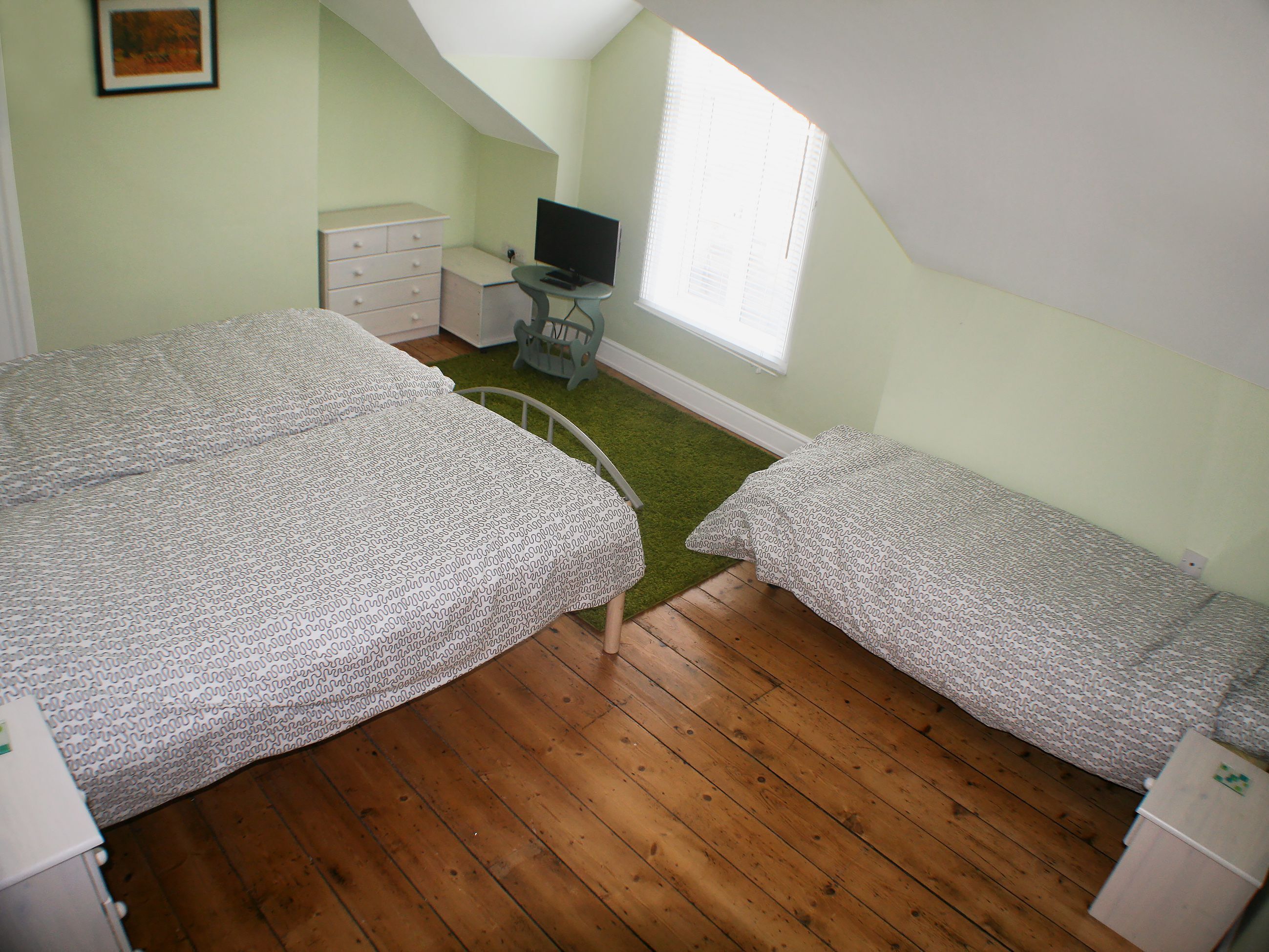 Un dormitorio con dos camas, un escritorio, una silla y una ventana.
