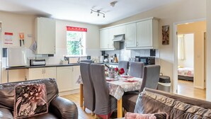 A modern kitchen with white cabinets, a dining area with a table set for four, and a living room with leather sofas. - 3 bedroom accommodation in Great Hatfield, near Hornsea (Great Hatfield, near Hornsea)