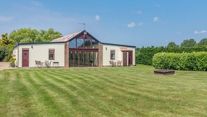 A two-story building with a large glass door entrance, a satellite dish on the roof, and a well-maintained lawn in front. - 3 bedroom accommodation in Great Hatfield, near Hornsea (Great Hatfield, near Hornsea)