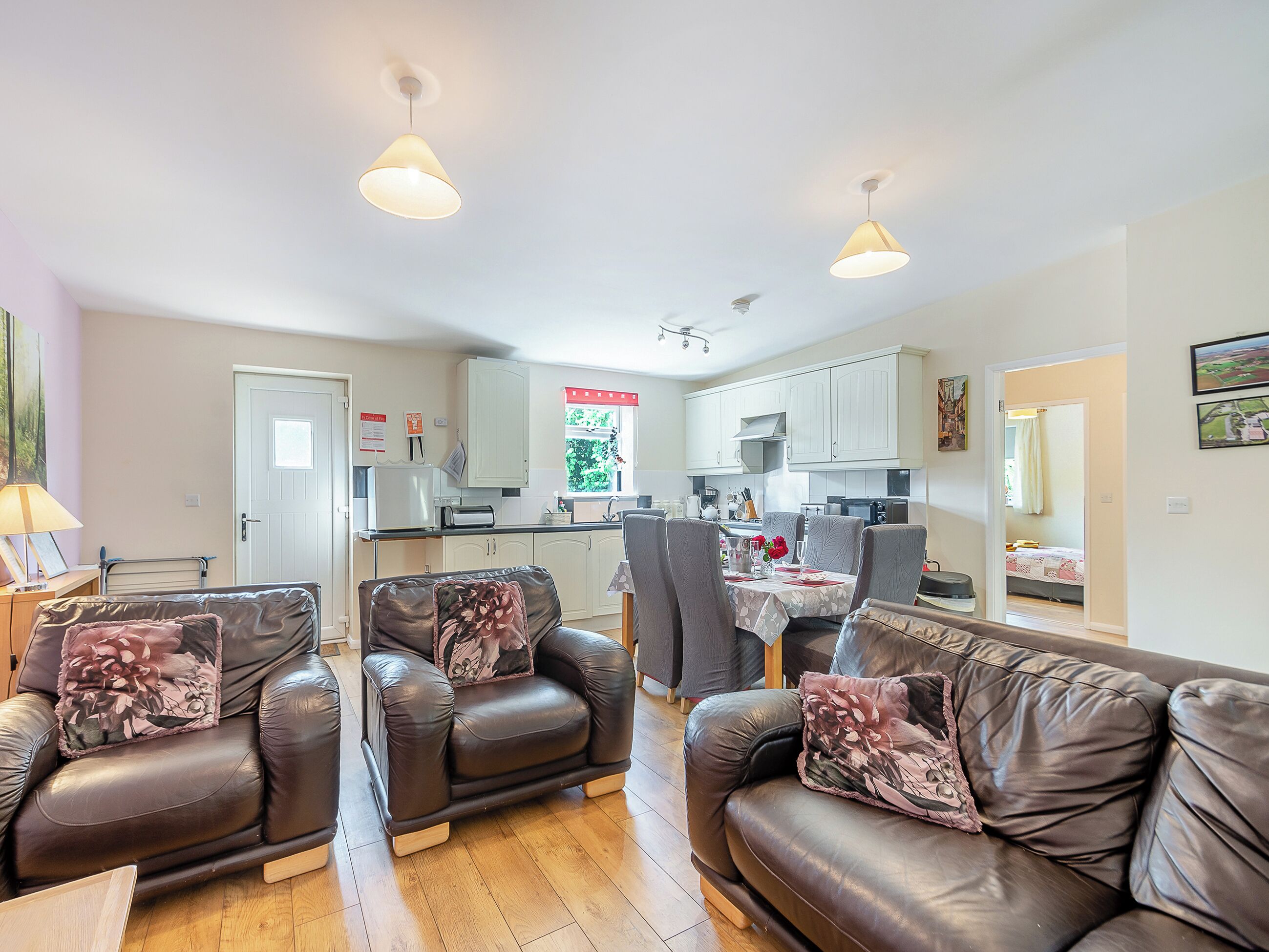 A living room with leather sofas and a dining area with a table and chairs.
