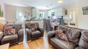A living room with leather sofas and a dining area with a table and chairs. - 3 bedroom accommodation in Great Hatfield, near Hornsea (Great Hatfield, near Hornsea)