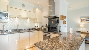 A modern kitchen with granite countertops, stainless steel appliances, and white cabinetry. - Apartment 14, Hazelwood Hall (Silverdale, near Arnside)